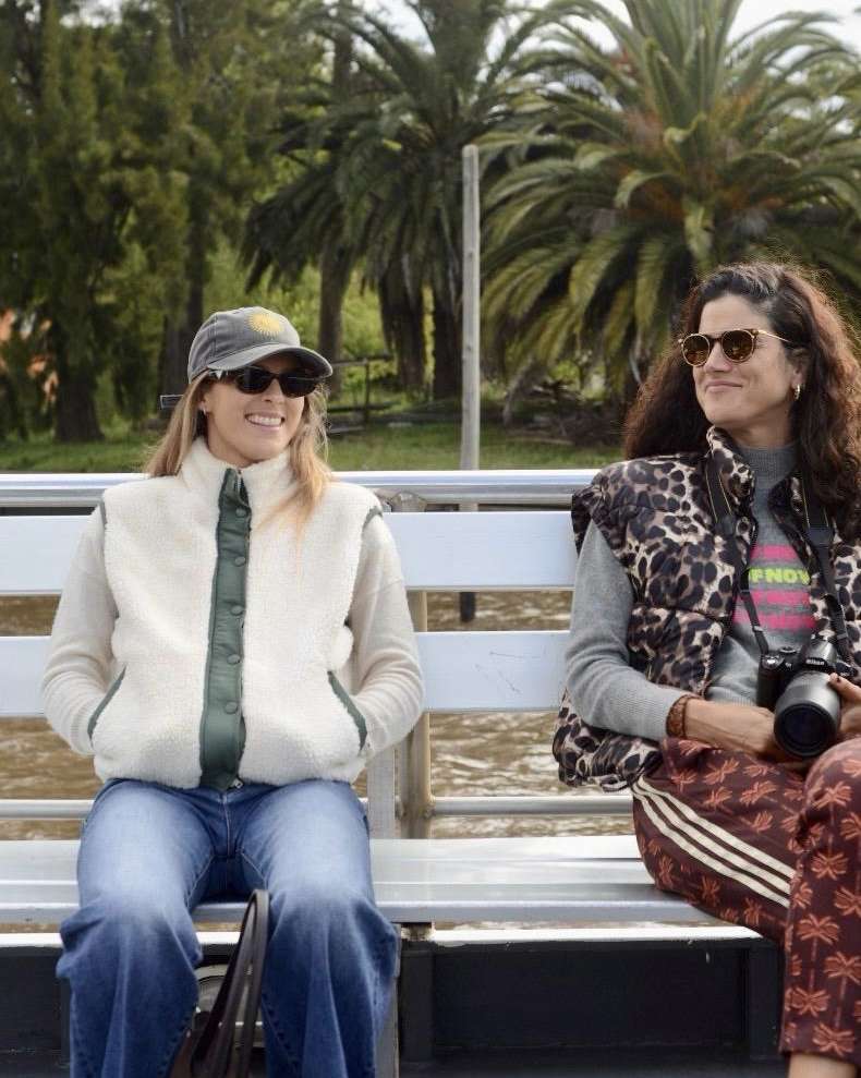 Dos viajeras descansando en un parque con palmeras